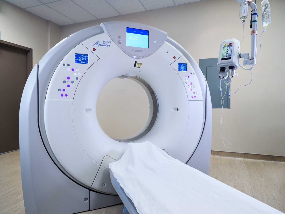 white CT scan machine in a plain hospital room