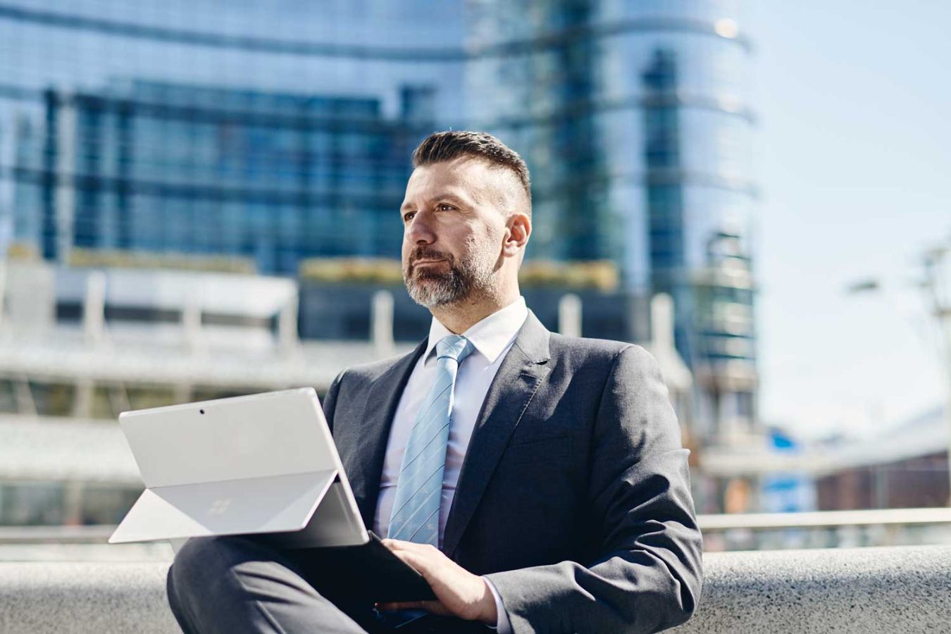 Man in a suit sitting outside on a laptop