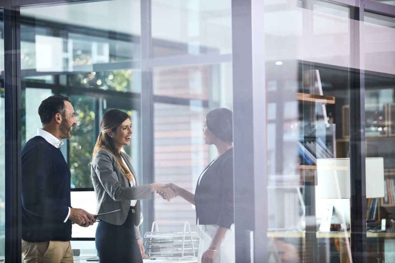 women in an office shaking hands with a man smiling