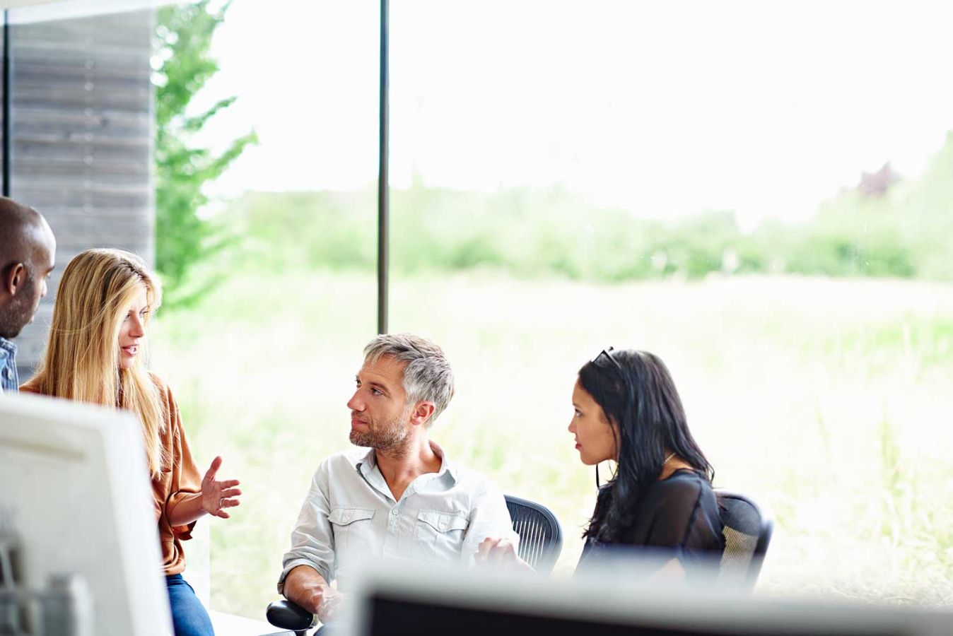 people sitting down in an office with a field in the background