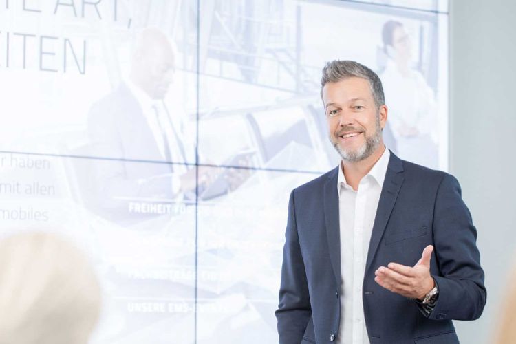 Man in suit presenting in-front of a screen